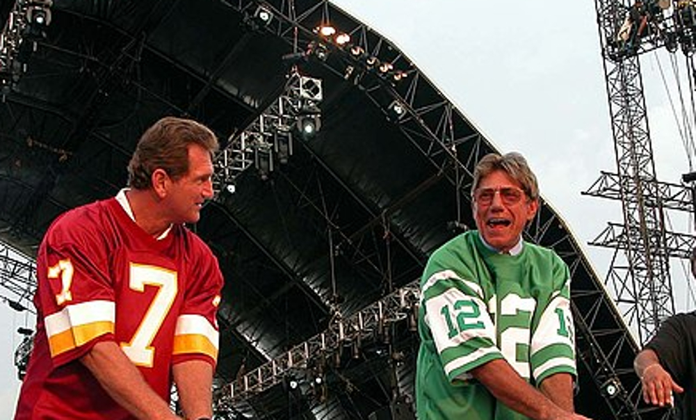 .Former_NFL_quarterbacks_Joe_Theismann_of_the_Washington_Redskins_and_Joe_Namath_of_the_New_York_Jets_clown_around_on_stage_before_the_opening_of_the_NFL_Kickoff_2003_celebration_Sept._4_on_the_National_Mall.jpg