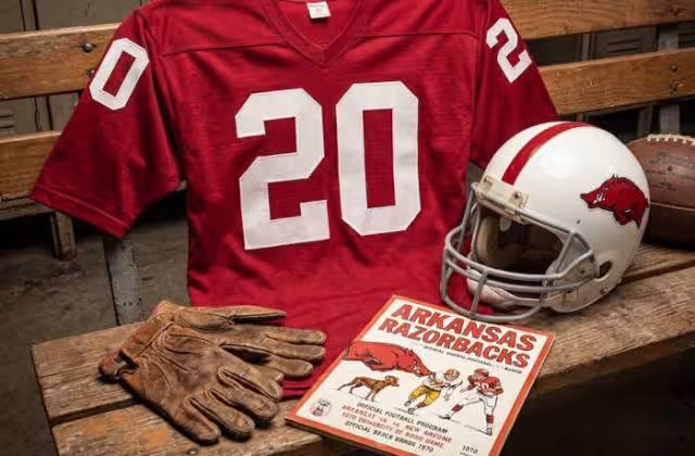 Gemini AI-created image of a 1970-era University of Arkansas American football jersey 20, without a name on it, and a matching period-correct helmet, the program cover appropriate to the era and team.