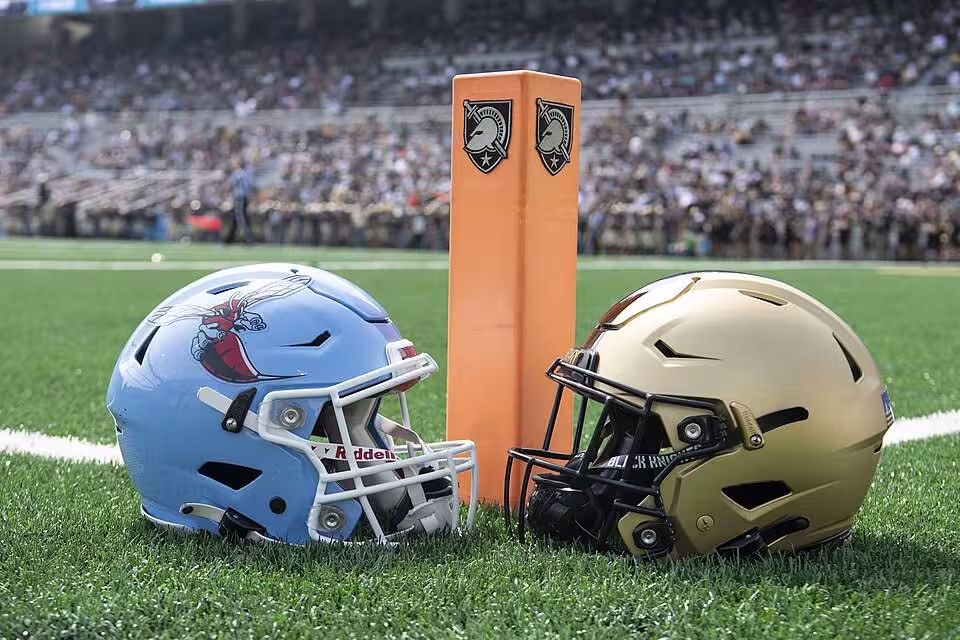 Color photo of a Deleaware Stae and an Army helmet in front of an orange pylon.