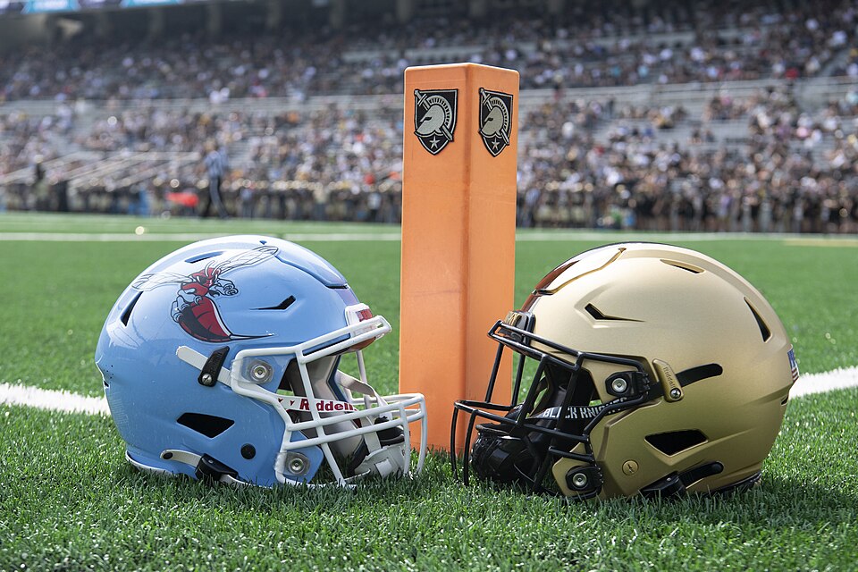 Color photo of a Deleaware Stae and an Army helmet in front of an orange pylon.
