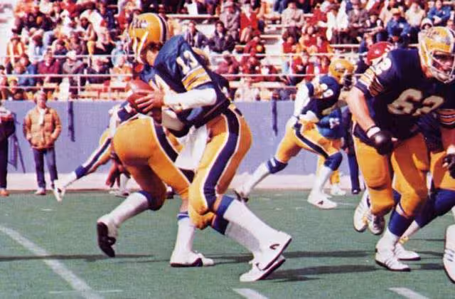 Full color game day action photo of Dan Marino quarterbacks the Pitt Panthers of the University of Pittsburgh in a football game at Pitt Stadium against the Cincinnati Bearcats on October 13, 1979. Pitt won the game 35-0.