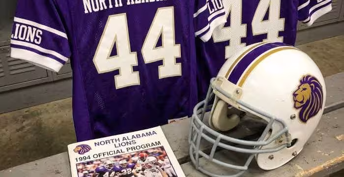 Gemini AI-created image of a 1994-era North Alabama American football jersey 44, without a name on it, and a matching period-correct helmet, the program cover appropriate to the era and team.