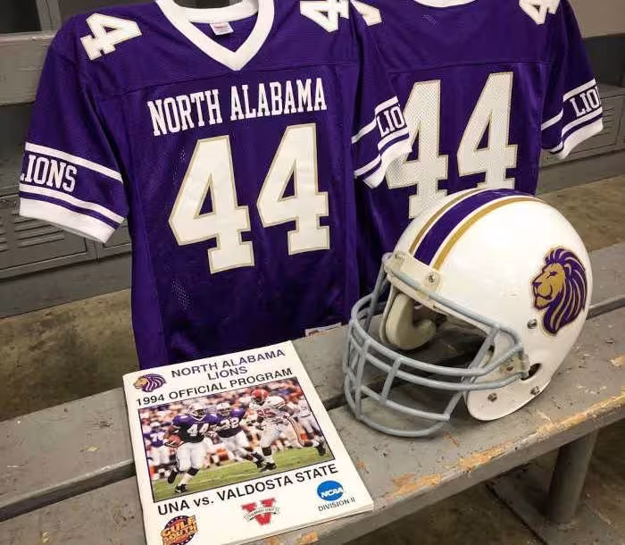Gemini AI-created image of a 1994-era North Alabama American football jersey 44, without a name on it, and a matching period-correct helmet, the program cover appropriate to the era and team.