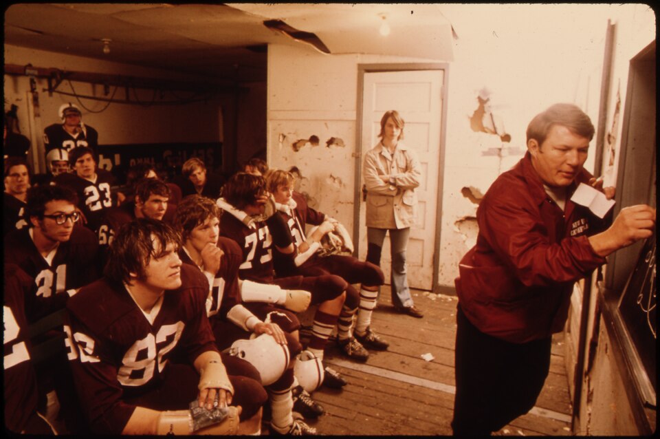 Landscape color photo of a high school locker room planning meeting before a game.