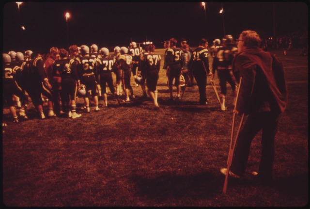 color blurry image of RIFLE VERSUS ASPEN HIGH SCHOOL FOOTBALL GAME. (ASPEN WON 14-13). SPECTATORS WATCH FROM THE SIDELINES AND FROM THEIR CARS - NARA