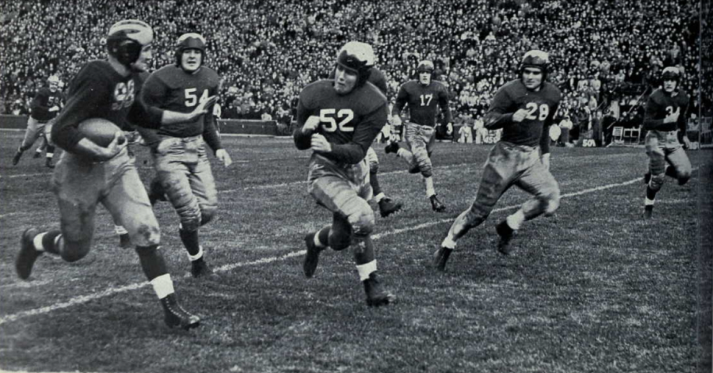 Black and white vintage game action photo of Tom Harmon of Michigan on his way to a TD with teammates.