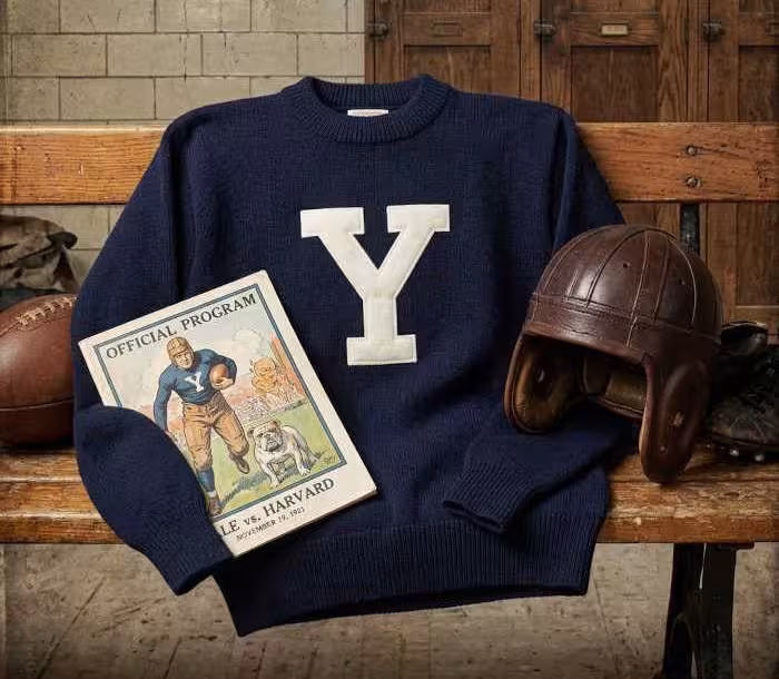 Gemini AI-created image of a 1921-era YaleAmerican football jersey sweater with a "Y" on thr front and nothing else, without a name on it, and a matching period-correct helmet, the program cover appropriate to the era and team.