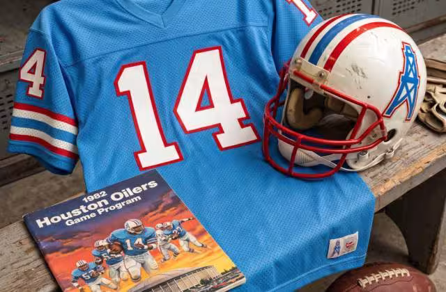 Gemini AI-created image of a 1982-era Houston Oilers American football jersey 14 jersey, without a name on it, and a matching period-correct helmet, the program cover appropriate to the era and team.