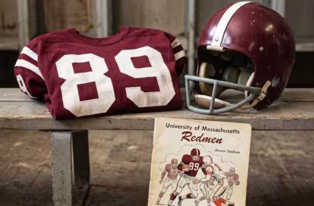 Gemini AI-created image of a 1965-era University of Massachussetts American football jersey 89, without a name on it, and a matching period-correct helmet, the program cover appropriate to the era and team.