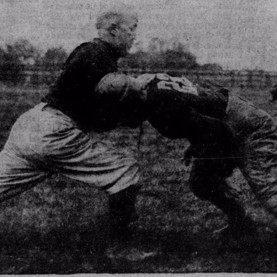 Black and White image of Knute Rockne giving instruction on blocking
