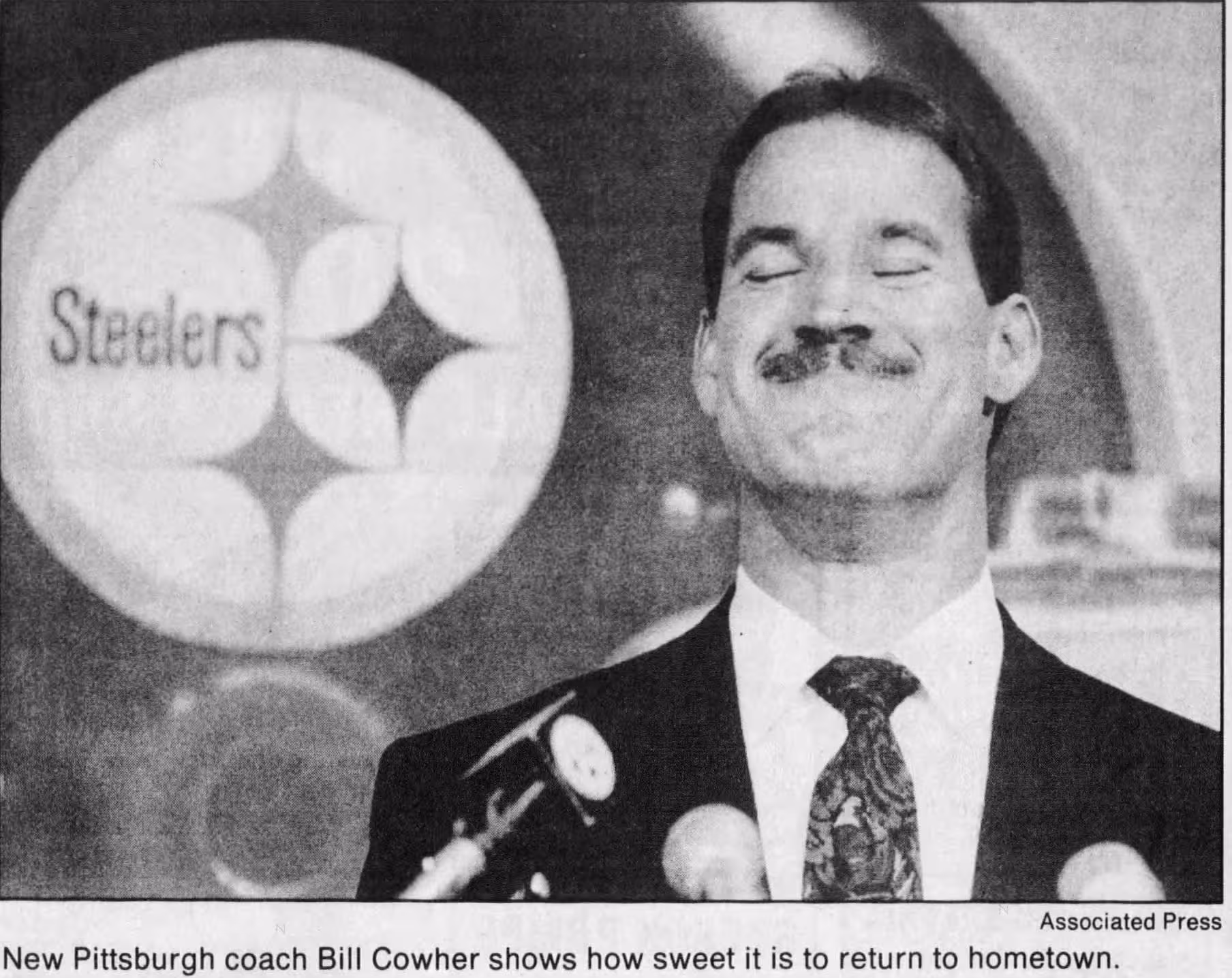 b/w newspaper image of Bill Cowher Hired as Steelers Coach 1992, with a giant image of a Steelers helmet image behind him