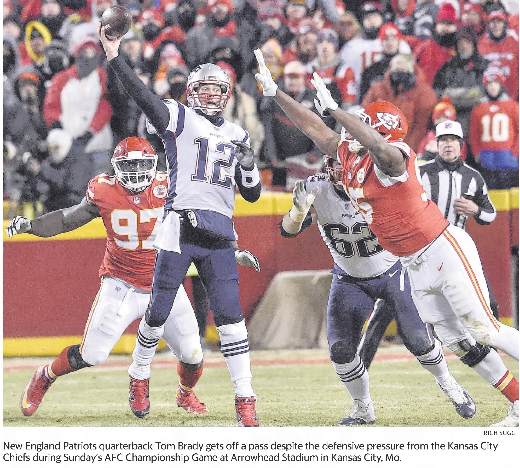 A newspaper photograph from the AFC Championship Game at Arrowhead Stadium. New England Patriots quarterback Tom Brady, wearing his white #12 jersey, is captured mid-throw as he releases a pass. He is under heavy defensive pressure from two Kansas City Chiefs players in red jerseys, including number 97. The background shows a crowded stadium and an official watching the play.