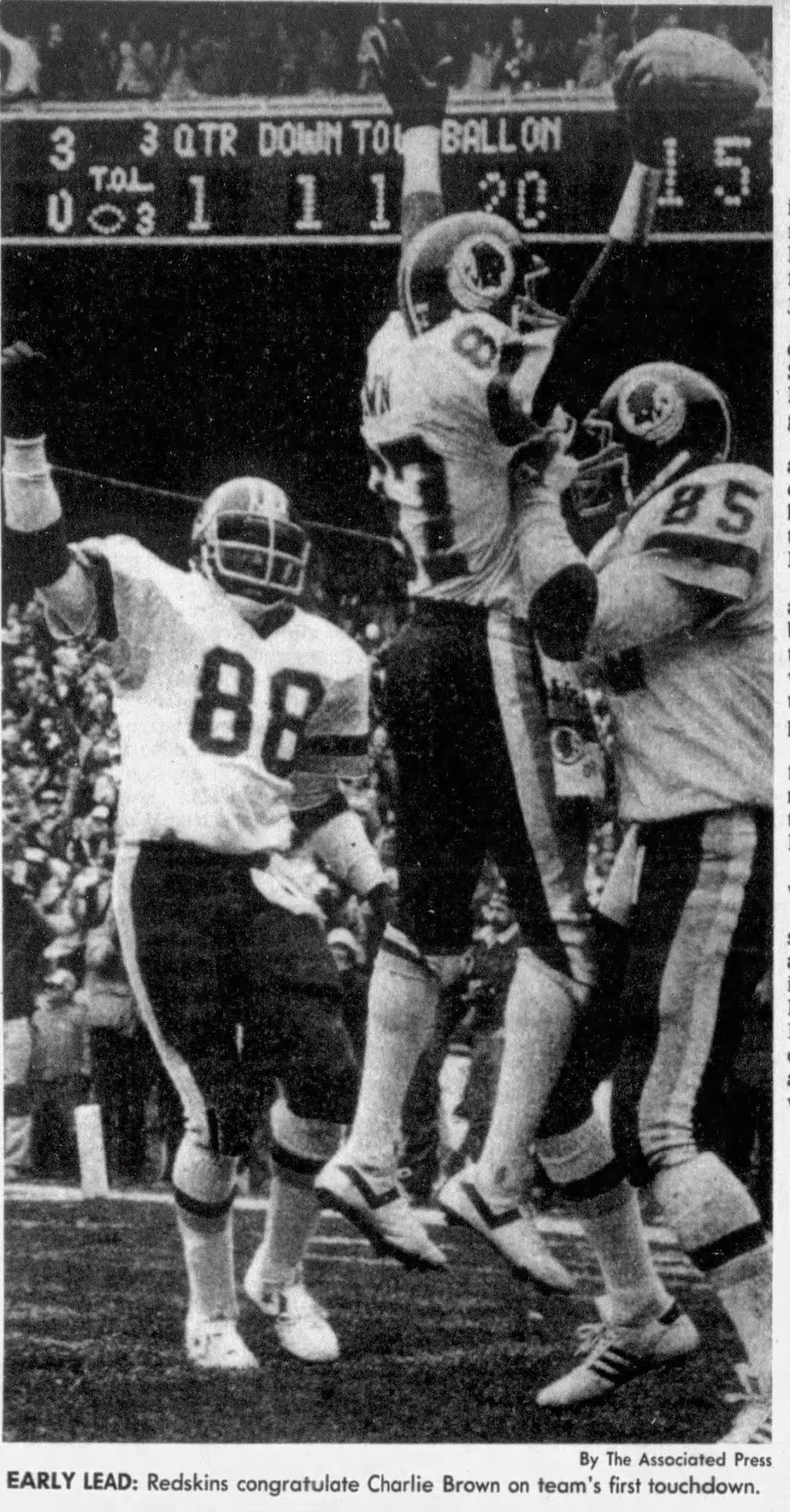 b/w newspaper image of Charlie Brown and other Washington Redskins in a TD celebration as Brown is lifted into the air by a teammate while holding the ball