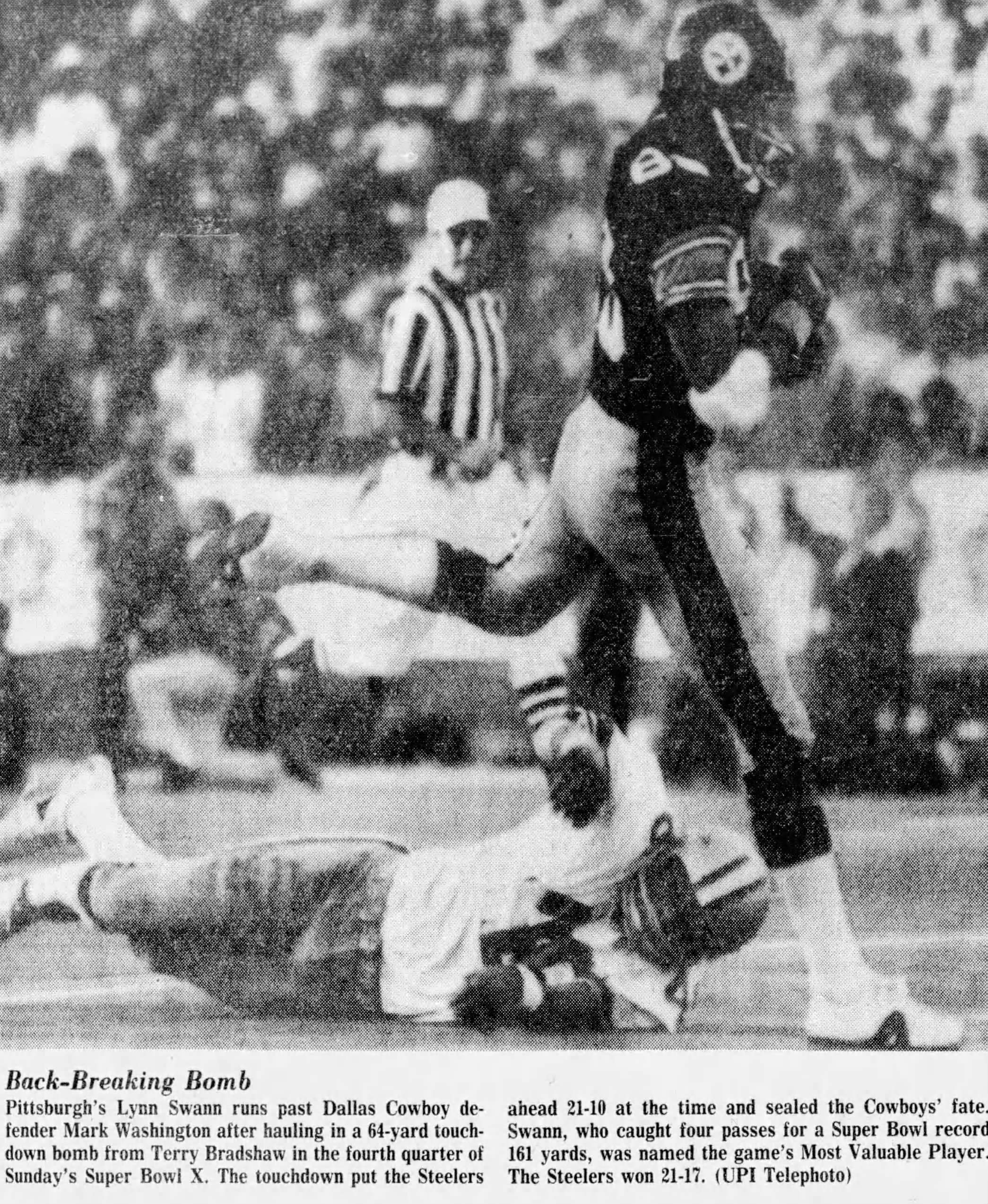 A black-and-white newspaper clipping titled 'Back-Breaking Bomb' from Super Bowl X. The photo shows Pittsburgh Steelers wide receiver Lynn Swann (#88) in mid-air, having just hauled in a 64-yard touchdown pass. Dallas Cowboys defender Mark Washington is pictured on the turf behind him. The caption details Swann’s record-breaking 161-yard performance and his MVP honors in the Steelers' 21-17 victory