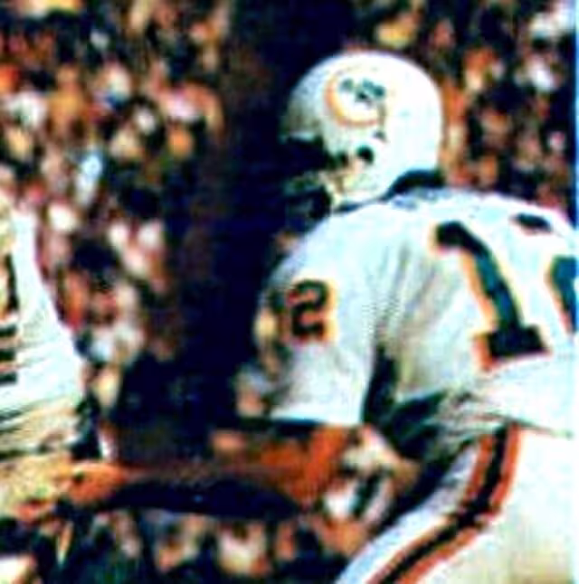a color action shot of Miami Dolphins quarterback Bob Griese pictured handing the ball to teammate Jim Kiick off for a running play
