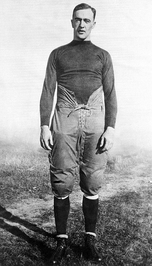 black and white full image of ND star George Gipp in full 1920s era football gear standing on a playing field