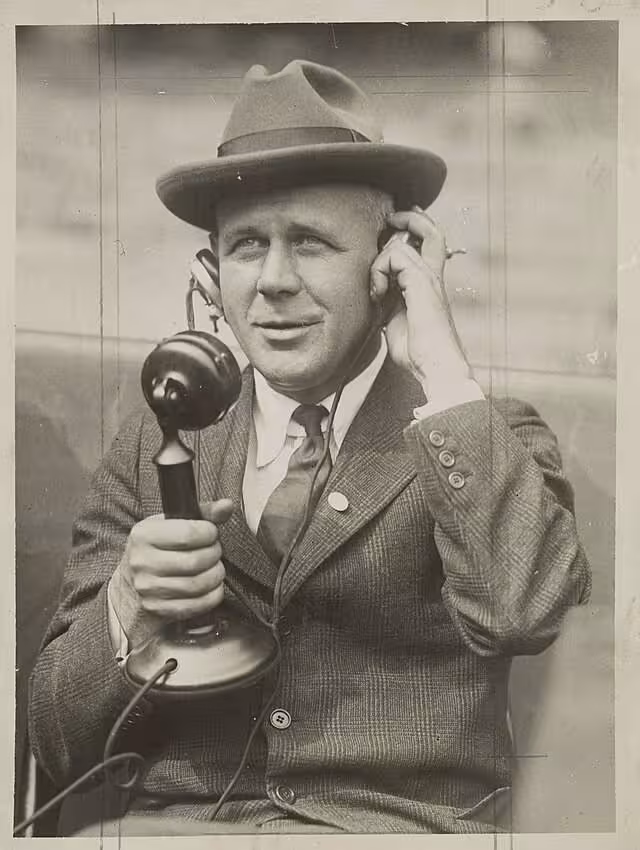 Grantland Rice on a candlestick looking telephone device circa 1920