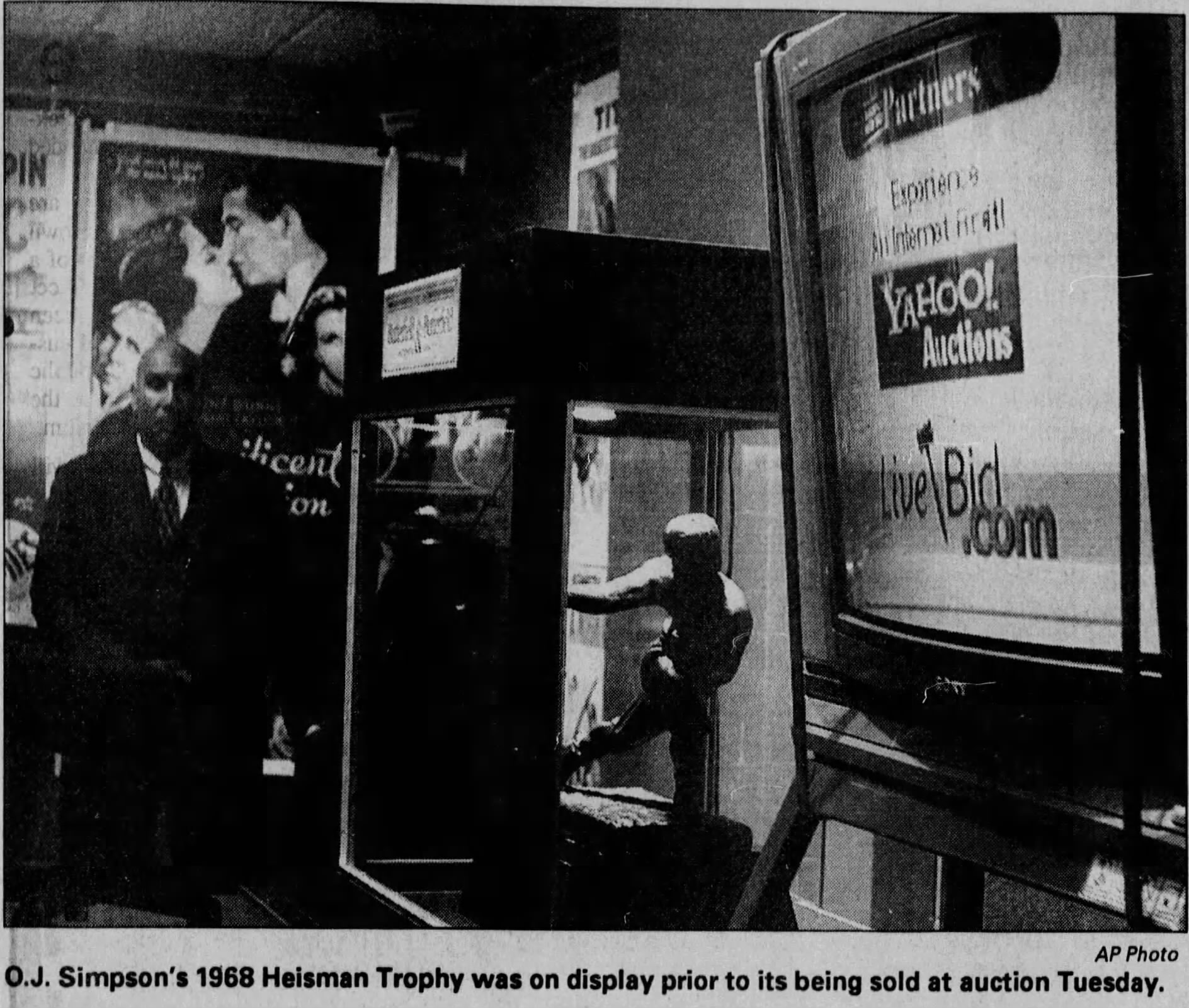 black and white newspaper clipping of OJ Simpson's heisman trophy under glass at auction, AP Photo