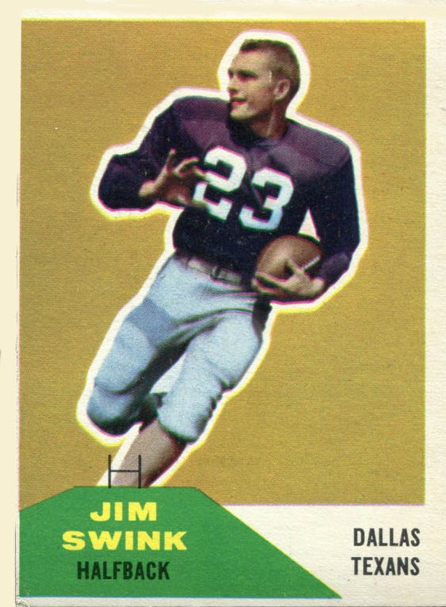 A vintage 1960 Fleer football card featuring Jim Swink, a halfback for the Dallas Texans. The card shows a colorized action shot of Swink running with a football, wearing a dark purple jersey with the number '23' and silver pants. The background is a solid gold color with a green nameplate at the bottom left.