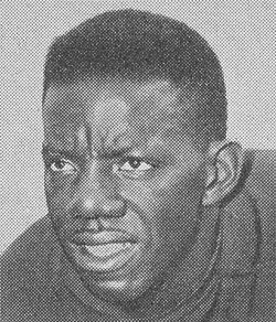 A black-and-white archival headshot of Chicago Bears running back Willie Galimore from 1960. The photo features a close-up of Galimore’s face with a serious, focused expression. He has short-cropped hair and is wearing a dark, high-collared jersey or jacket. The image has a distinct halftone dot pattern, indicating it was reproduced from a vintage newspaper or team yearbook.
