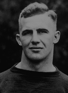 A black-and-white archival portrait of Pittsburgh football standout Herb Stein from 1921. The photo shows Stein from the chest up, featuring a classic early 20th-century 'high and tight' haircut and a stoic expression. He is wearing a dark, heavyweight wool jersey with a simple rounded collar. The lighting is direct, emphasizing the physical presence of the All-American center.