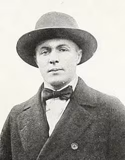 A black-and-white studio portrait of Herbert Young from the College of William & Mary. He is wearing a dark, heavy-knit vintage football sweater with a high ribbed collar and a light-colored 'W' patch sewn onto the chest. He is looking slightly off-camera with a serious expression.