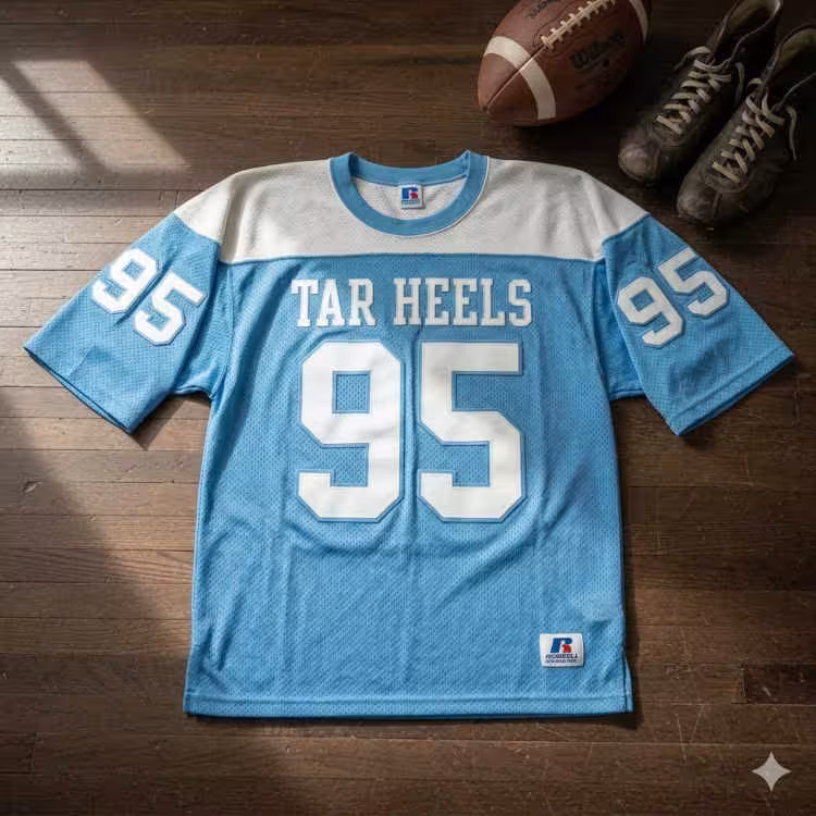 Vintage North Carolina Tar Heels #95 jersey displayed on a wooden floor with a leather football and antique cleats.