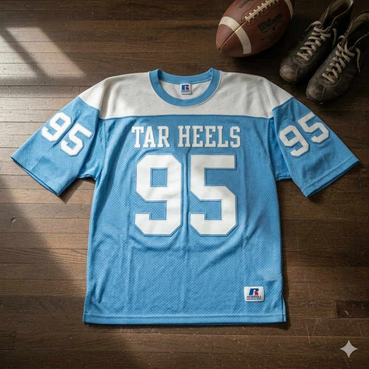 Vintage North Carolina Tar Heels #95 jersey displayed on a wooden floor with a leather football and antique cleats.