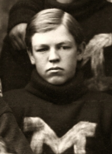 A sepia-toned vintage portrait of William Morley from 1895. He is shown from the chest up, wearing a dark, heavy-knit turtleneck football sweater with a large, light-colored 'M' varsity letter on the chest. He has short, side-parted hair and a solemn expression, typical of 19th-century athletic photography.
