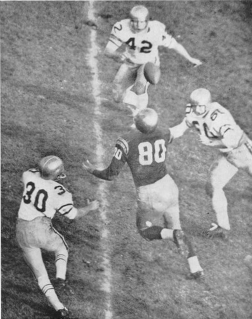 Vintage black and white game action photo of Scene from the 1959 American football game between the Georgia Tech Yellow Jackets and the Notre Dame Fighting Irish. The image depicts Notre Dame player Monty Stickles (No. 80) attempting to catch a pass while surrounded by three Georgia Tech players: Billy Williamson (No. 30), Ben Smith (No. 42), and Bill McKinney (right).