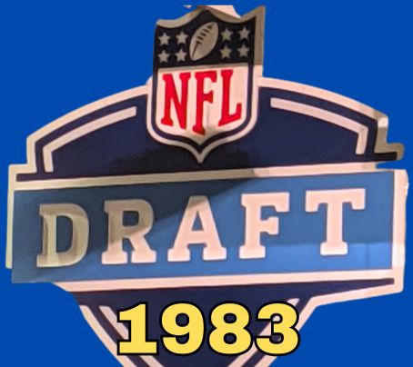 NFL Draft sign in color on a blue background with the year 1983 text across the bottom in yellow. The original cropped image was taken by Darin Hayes at AT&T Stadium in 2022.