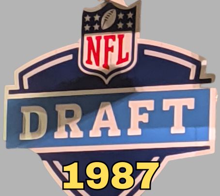 NFL Draft sign in color on a gray background with the year 1987 text across the bottom in bright yellow. The original cropped image was taken by Darin Hayes at AT&T Stadium in 2022.
