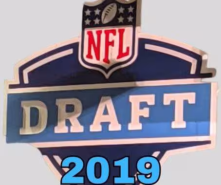 NFL Draft sign in color on a gray background with the year 2019 text across the bottom in bright blue. The original cropped image was taken by Darin Hayes at AT&T Stadium in 2022.
