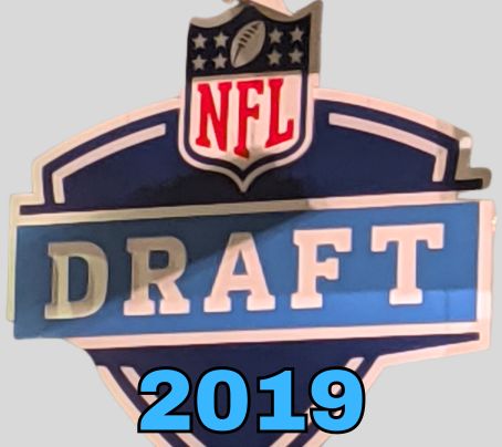 NFL Draft sign in color on a gray background with the year 2019 text across the bottom in bright blue. The original cropped image was taken by Darin Hayes at AT&T Stadium in 2022.