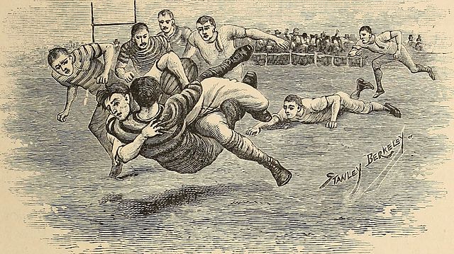 A highly detailed black-and-white 19th-century etching of a football game in progress. In the foreground, a player in a striped jersey is being tackled mid-air by an opponent while clutching the ball. Surrounding players are shown in various states of action: one lunges for a low tackle, others rush toward the pile, and a goalpost is visible in the background. The players wear period-appropriate attire including long-sleeved jerseys, knicker-style trousers, and high-top boots, with no helmets or padding. The artist's signature, 'Stanley Berkeley,' is visible in the lower right corner.