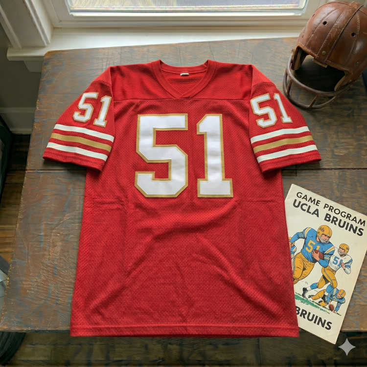 Vintage San Francisco 49ers #51 football jersey. Red mesh with white and gold shadowed block numbers and triple-striped sleeves. Features a 1980s UCLA Bruins game program and a vintage leather helmet for historical NFL and Pac-12 research for Pigskin Dispatch archives.