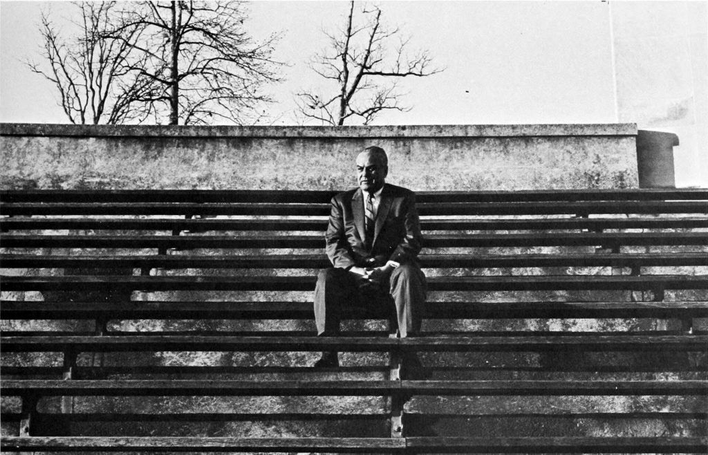 black and white vintage Image of Eddie Cameron sitting on the empty Duke bleachers.
