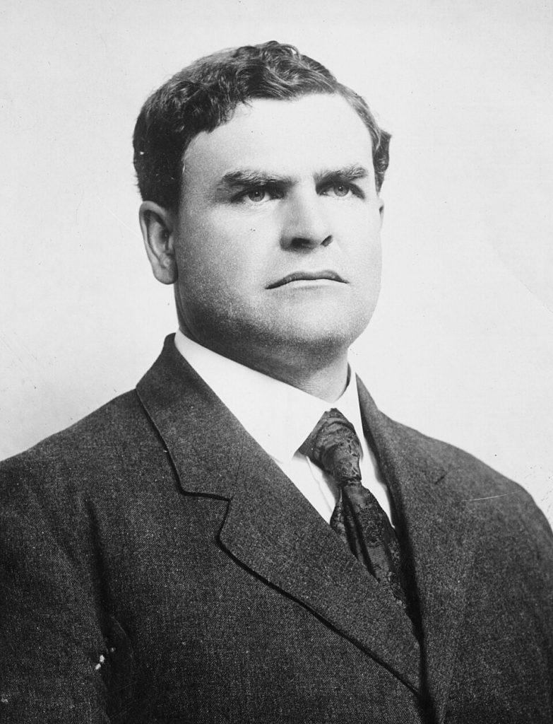 Archival studio portrait of legendary innovator Glenn 'Pop' Warner, the mastermind behind the single-wing formation and modern coaching techniques.