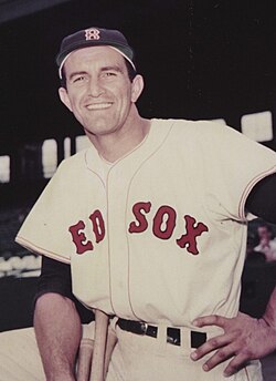 Vintage color archival portrait of Boston Red Sox first baseman and Boston University football legend Harry Agganis. Features Agganis in a cream Red Sox home uniform at Fenway Park. A primary source for multi-sport athlete research and New England sports history for Pigskin Dispatch archives.