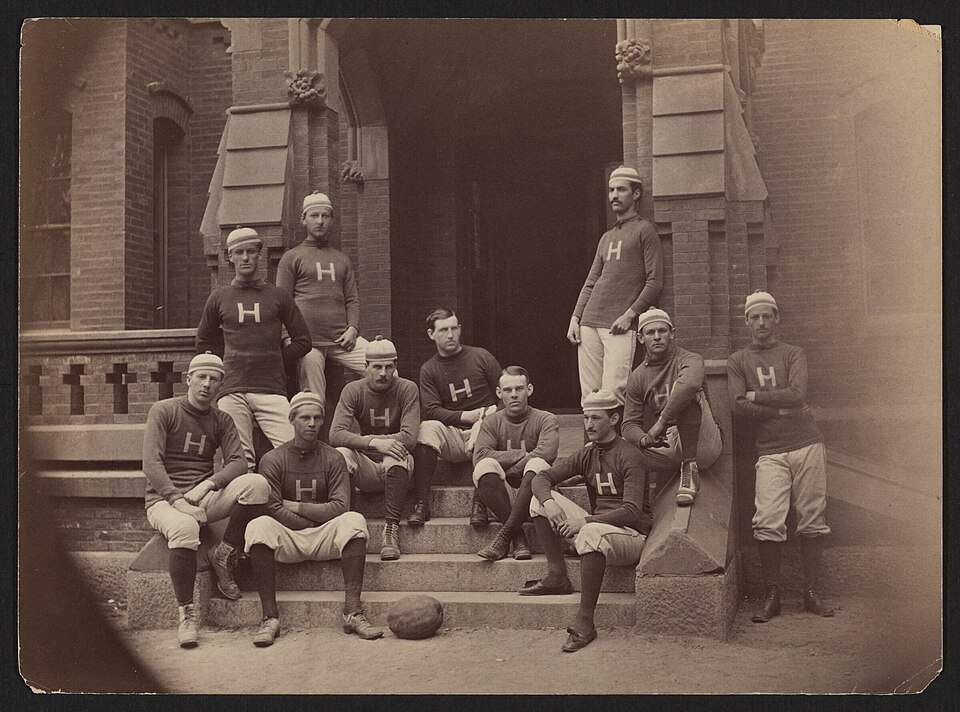Vintage black and white team photo on the concrete steps of a building of the Harvard Football Team, 1878