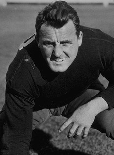 black and white publicity image of Jack Cannon in his Notre Dame football uniform of the era in a stance