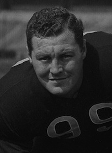 Vintage black and white photo of Ohio State University tackle Jim Daniell. Daniell is shown in a football stance wearing a dark #99 Buckeyes jersey for historical collegiate sports research and Pigskin Dispatch archives.