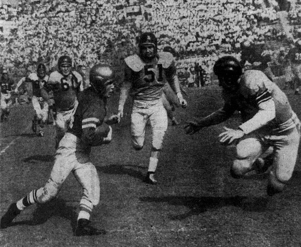 Vintage black and white game action photo of Loyola Lions player Bob Burton (left) rushes the ball as San Diego Navy defender Earl Stelle (far right) closes in for the tackle during a game on September 23, 1951 at the Rose Bowl in Pasadena, California.