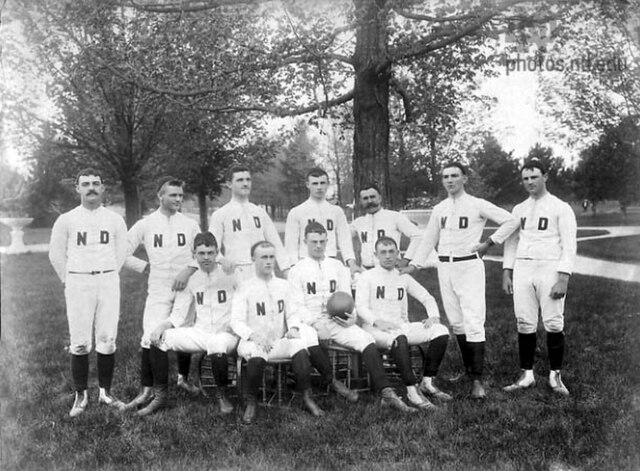 "Inaugural 1887 Notre Dame football team archival photo. Black and white group portrait of the first Notre Dame squad wearing canvas uniforms with hand-sewn 'ND' monograms. A foundational primary source for college football history and Pigskin Dispatch archives.