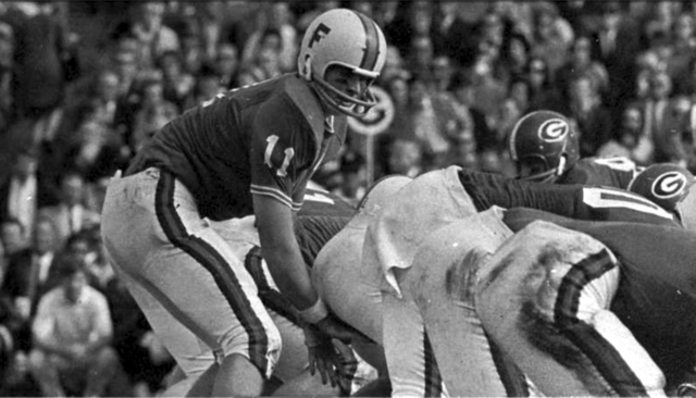 Vintage 1966 archival action photo of Florida Gators quarterback Steve Spurrier (#11) under center against the Georgia Bulldogs. Features the classic 'F' logo helmet and 1960s SEC uniform style. A primary source for Heisman Trophy history and Pigskin Dispatch archives.