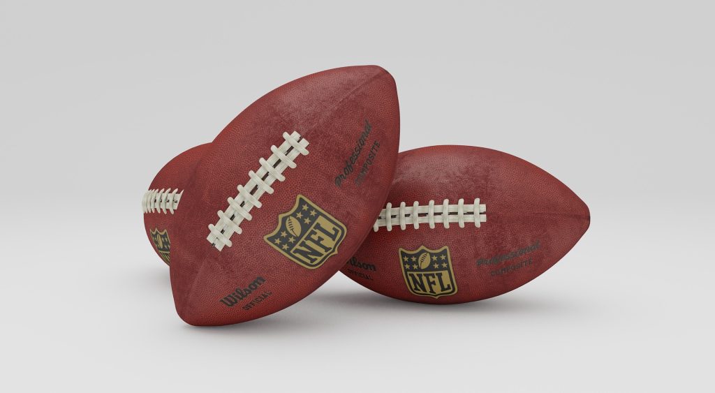 color Photo of three NFL footballs positioned with strings facing camera.