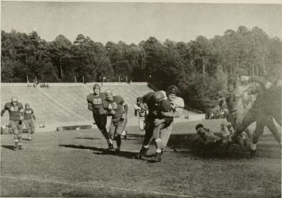 Vintage, black and white, game action photo of Scene from a college football game between the North Carolina Tar Heels and the William & Mary Indians at Kenan Memorial Stadium, November 11, 1944. Caption reads "Smith stops and Indian for no gain".