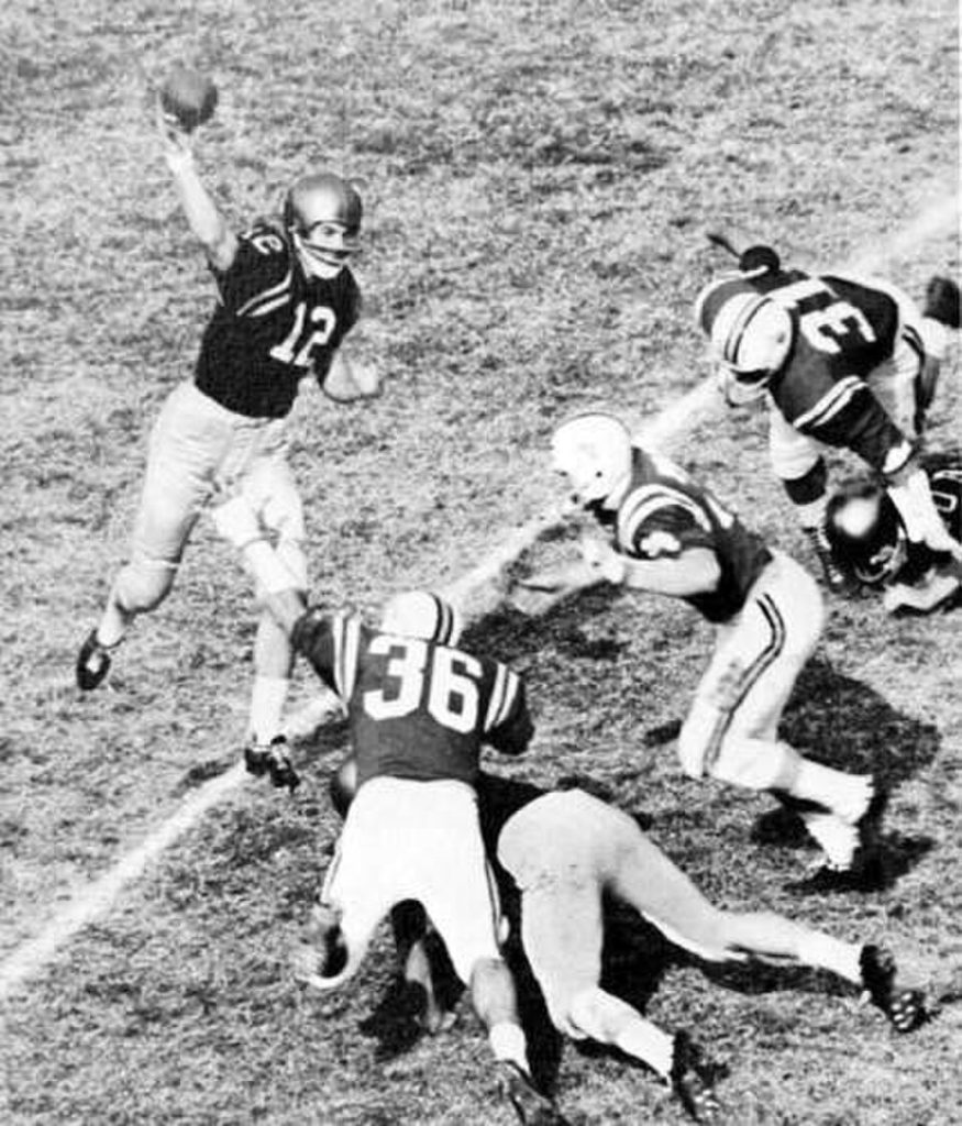 Vintage black and white game action photo of Navy quarterback, Roger Staubach (#12), attempts a forward pass as Maryland defenders close in.