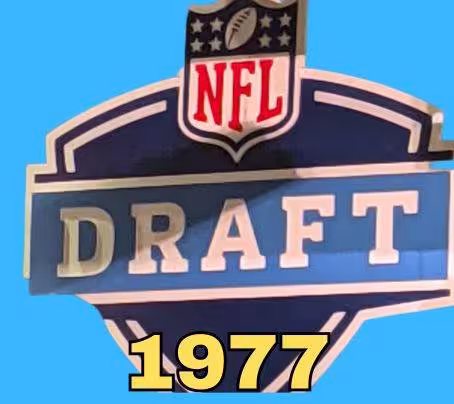 NFL Draft sign in color on a blue background with the year 1977 text across the bottom in yellow. The original cropped image was taken by Darin Hayes at AT&T Stadium in 2022.