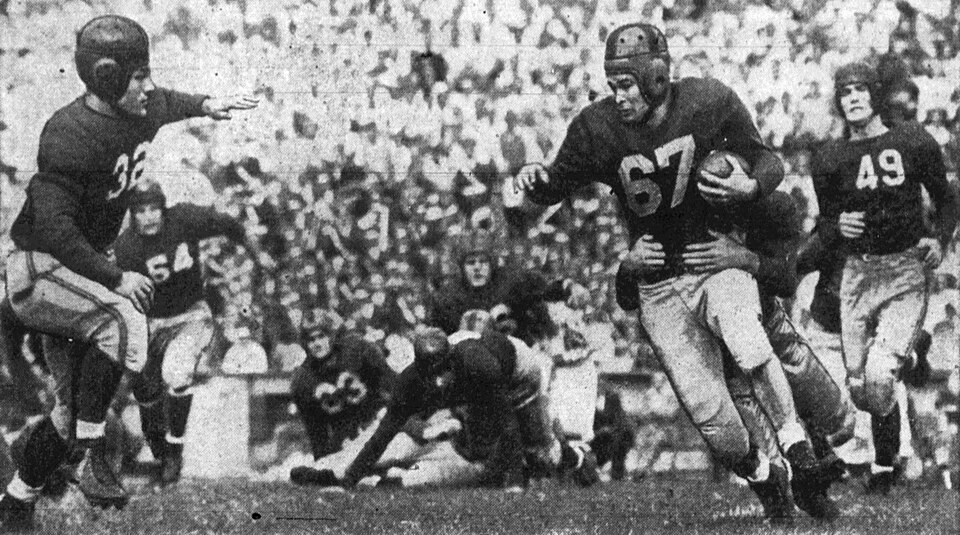 Classic black and white game action image of California Golden Bears halfback Al Derian (right, number 67) makes a seven yard gain before being tackled by Santa Clara Broncos guard Dave Simmons as defenders Ray Bradford (right, number 49) and Jerry Zapelli (left, number 32) close in. The game took place on October 11, 1941 at Memorial Stadium in Berkley, California.